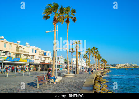 PAPHOS, Zypern - 13. FEBRUAR 2019: Menschen auf Paphos Promenade bei Sonnenuntergang. Paphos ist die berühmte touristische Destination in Zypern Stockfoto