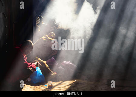 Marrakesch, Marokko - Dezember 30, 2017: Ein alter Mann im Souk Haddadine sitzt, mit Sonnenlicht in der dunklen von oben Stockfoto