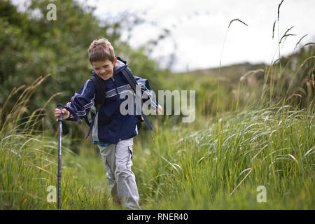Happy Boy wandern durch hohes Gras Stockfoto