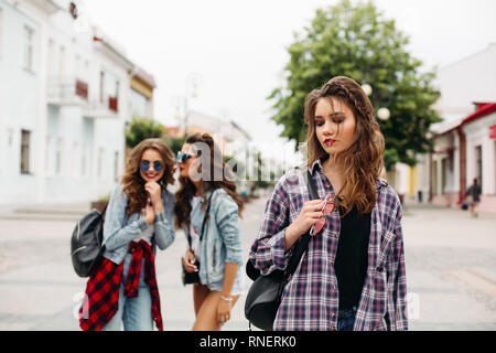 Eifersüchtig Mädchen Flüstern über dritte Mädchen vor der Kamera. Stockfoto