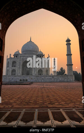 Taj Mahal bei Sonnenaufgang gerahmt mit dem Bogen der Moschee, Agra, Uttar Pradesh, Indien. Taj Mahal wurde 1983 zum UNESCO-Weltkulturerbe erklärt. Stockfoto