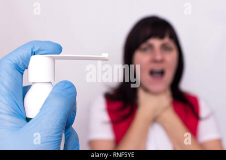 Arzt hält spray Medizin für Halsschmerzen, im Hintergrund ein Mädchen, das sich Hals Halsschmerzen und Halsschmerzen, Infektionen, Pharyngitis Stockfoto