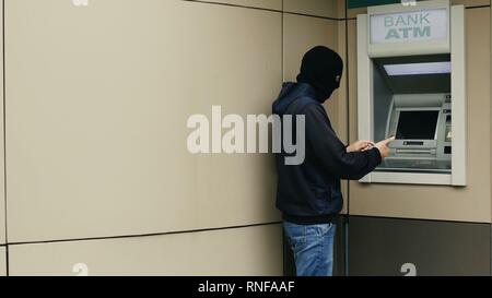 Dieb mit Smartphone stiehlt Informationen aus einer Bank ATM Stockfoto