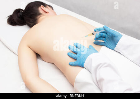 Ein Arzt macht einen Schuß mit Plasma in der wirbelsäule von einem Mädchen, das Patienten, die Probleme hat, die Behandlung mit Plasma- Therapie, Entzündung Stockfoto