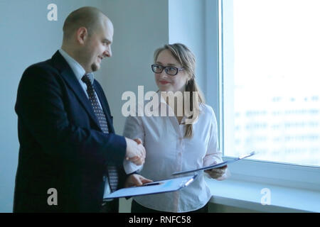 Unternehmer und Business woman Hände schütteln stehen in der Nähe der Fenster Stockfoto