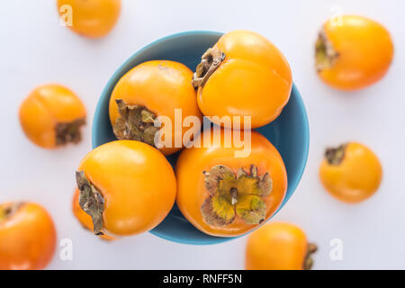 Selektiver Fokus der reife Persimonen auf blauen Glasplatte Stockfoto