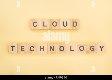 Blick von oben auf die Cloud-technologie Schriftzug von Holzwürfeln auf gelbem Hintergrund Stockfoto