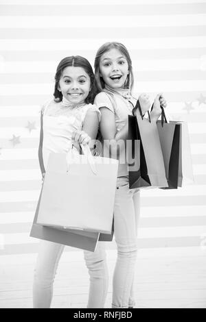 Mädchen wie einkaufen. Die Kinder glücklich kleine Mädchen halten Einkaufstaschen. Viel Spaß beim Shoppen mit der besten Freundin oder Schwester. Mädchenhafte Glück. Die Kinder glücklich tragen Bündel Pakete. Einkaufen mit beste Freundin Konzept. Stockfoto