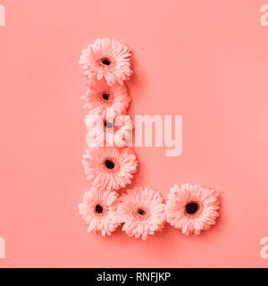 Buchstabe L aus Blumen Gerbera auf einem farbigen Hintergrund des Jahres 2019 Lebende Korallen Pantone. Ein Teil des Wortes Liebe. Ansicht von oben. Für Text platzieren. Stockfoto