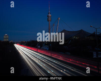 München, Deutschland - 14. Februar 2019: Olympia Turm und das Olympia Stadion München mit Diagonalen rush hour Ampel in der Zwiebel Exposition während der Dämmerung Stockfoto