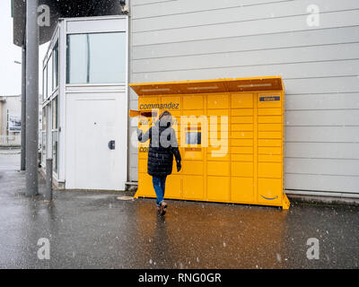 Straßburg, Frankreich - Feb 8, 2018: Junge Frau mit Amazon Spind die Self-service-Paketdienst Station in der Nähe von Auchan Supermarkt die Tür öffnen Blick in Karton abrufen Stockfoto