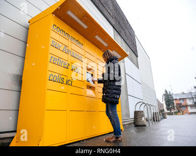 Straßburg, Frankreich - Feb 8, 2018: Junge Frau mit Amazon Spind die Self-service-Paketdienst Station in der Nähe von Auchan Supermarkt Wide Weitwinkel Winter schneebedeckten Tag Stockfoto