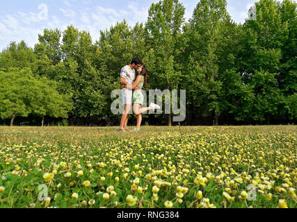 Glücklich liebend Paar küssen einander in einem Feld voll mit gelben Blumen. Stockfoto