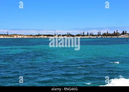 Klare blaue Meer mit Strand und Palmen auf dem Horizont und ein strahlend blauer Himmel Stockfoto