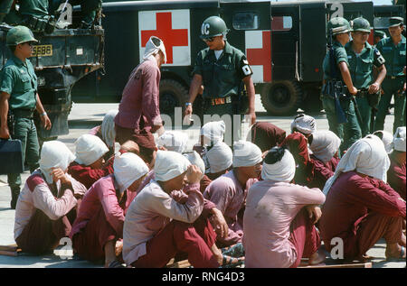 Viet Cong Kriegsgefangenen sitzen auf der Rampe bei Tan Son Nhut Air Base unter den wachsamen Augen der Südvietnamesischen Militärpolizei. Die Kriegsgefangenen zu Loc Ninh, Südvietnam für die Gefangenen Austausch zwischen den Vereinigten Staaten und Nord/Süd Vietnam Vietnam/Viet Cong Militär eingeflogen werden. Stockfoto