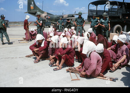 Viet Cong Kriegsgefangenen sitzen auf der Rampe bei Tan Son Nhut Air Base unter den wachsamen Augen der Südvietnamesischen Militärpolizei. Die Kriegsgefangenen wurden auf der Airbase in der 6x6-Lkw im Hintergrund geholt und wird zu Loc Ninh, South Vietnam auf der C-123 Transportflugzeuge für die Gefangenen Austausch zwischen den Vereinigten Staaten und Nord/Süd Vietnam Vietnam/Viet Cong Militär eingeflogen werden. Stockfoto