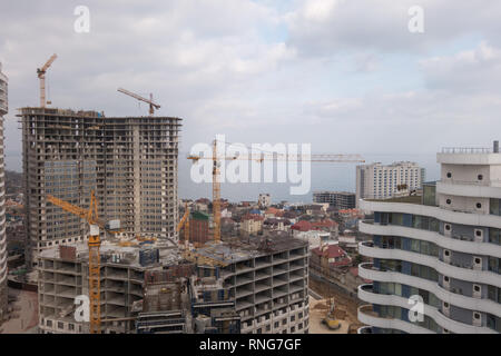 Bau eines Wohngebäudes, der am Ufer des Meeres steigen. Turmdrehkrane. Stockfoto