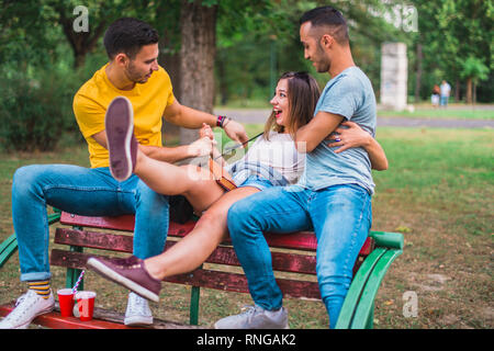 Freunde sitzen auf einer Bank im Park, Witze und Spaß haben Stockfoto