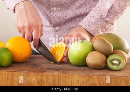 Mann schneidet Obst auf einem Holz Schneidebrett Stockfoto