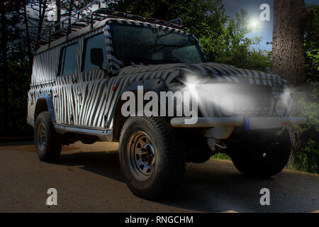 Safari Jeep mit Zebramuster Antriebe durch eine wunderschöne Natur mit Bäumen und Büschen von einem Nationalpark Europas Stockfoto