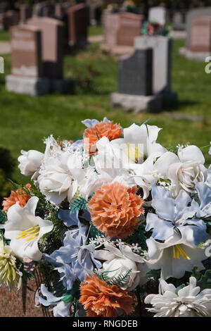 Close-up ein Bouquet von künstlichen Blumen auf einem Grabstein auf einem Friedhof Stockfoto