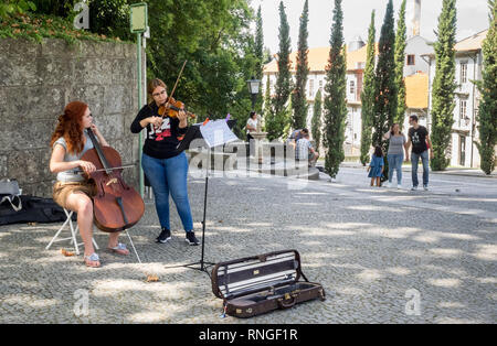 Zwei 2 weibliche Junge kaukasier Damen Musik Musikinstrument Gaukler Straßenmusik in der kopfsteingepflasterten Straße in Guimaraes in Portugal Stockfoto