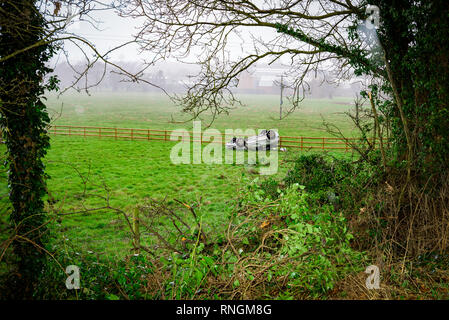 Auto Crash und Auto beschädigt; Fahrzeug kopfüber in ein Feld nach Kollision mit hoher Geschwindigkeit. Stockfoto