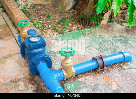 Ventile wasser Messing mit Knopf grün am Anschluss alte Rohr Stahl Farbe blau. auf dem Zementboden außerhalb der Industrie. Stockfoto