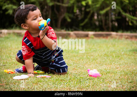 Cute indischen Kleinkind spielen mit seinem Spielzeug in einen Garten, Pune, Maharashtra Stockfoto