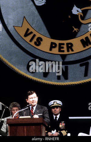 1982 - Senator John Tower, R - Texas, spricht während der Inbetriebnahme Zeremonie für die Atom-Flugzeugträger USS CARL VINSON (CVN-70). Sitzt hinter ihm sind CAPT Richard L. Martin, kommandierender Offizier der Carl Vinson, und Molly Snead, das Schiff ist Sponsor. Stockfoto