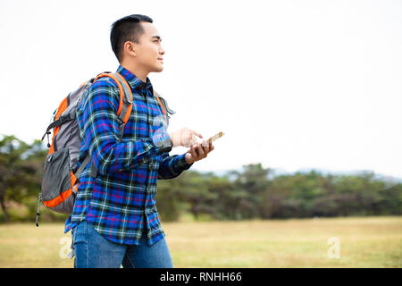 Junger Mann genießen Sie wandern Reise und sein Telefon surfen Stockfoto