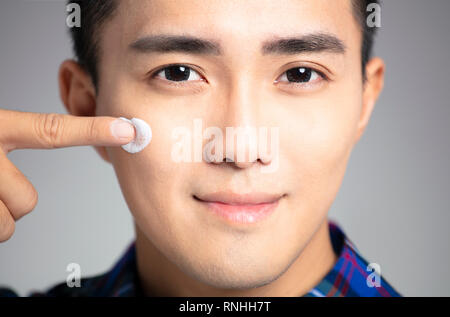Closeup junger Mann Anwendung Gesichtscreme Stockfoto