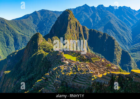 Die ersten Sonnenstrahlen scheint auf die Verlorene Stadt der Inkas Machu Picchu, mit seiner grünen landwirtschaftlichen Terrassen, Gehäuse und Huayna Picchu peak in der Nähe von Cusco, Peru. Stockfoto