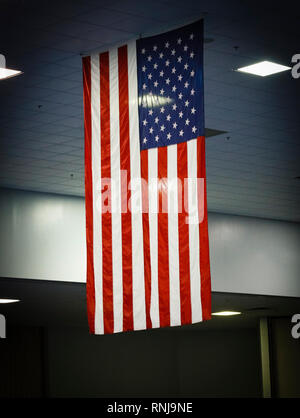 Eine amerikanische Flagge hängt von der Decke in einem Gebäude über alles andere. Stockfoto