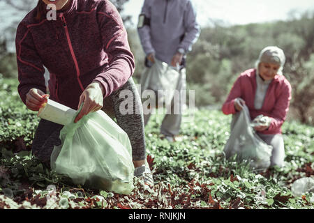 Frau in der roten Jacke, Papier, Glas in Müllsack Stockfoto