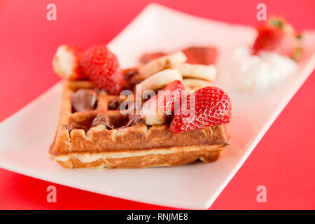 Erdbeere und Banane Waffel auf rotem Hintergrund Stockfoto