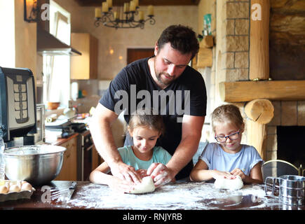 Vater und seine zwei kleinen Helfer. Kinder kochen hausgemachtes Brot mit es Vater Stockfoto