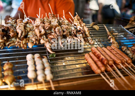 Asiatische Street Food präsentieren auf dem Markt in Bangkok, Thailand. Es gibt Sticks mit gebratenen Tintenfische, Fleisch- und Wurstwaren. Closeup horizontale Foto. Stockfoto