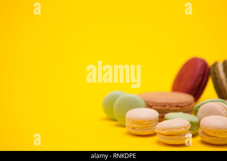 Wenig butter Creme amaretti Aromen neben verschiedenen Macarons auf gelben Hintergrund. Bunte Makronen Stockfoto