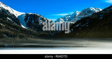 Schöne Berglandschaft mit früh Morgens Nebel auf Antholz - Antholzer Siehe zugefrorenen See, im Pustertal, Südtirol, Südtirol, Alpen in Stockfoto