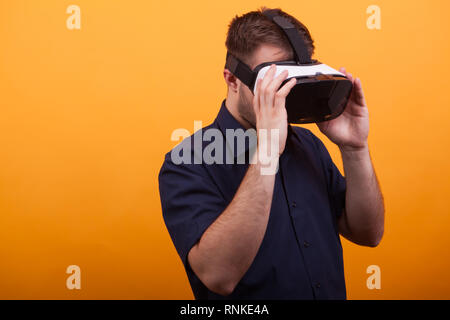 Junger Mann mit VR-Headset auf gelben Hintergrund Bärtigen. Futuristische Werkzeug Stockfoto