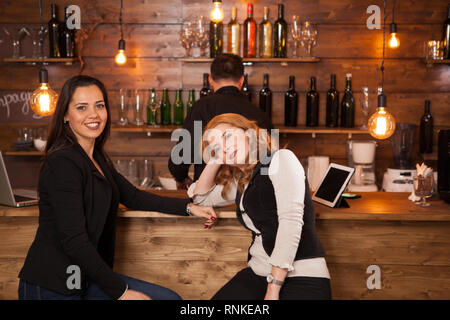 Zwei junge schöne Frauen im Gespräch in der Kneipe. Spaß in einem hipster Pub. Stockfoto