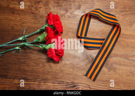 Symbole des Sieges im Großen Vaterländischen Krieg drei rote Blume und die Nummer 9 auf dem Tisch. selektive Fokus Bild Stockfoto