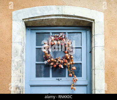 Vorderansicht eines Weihnachtskranzes aus trockenen Blumen und Pflanzen in Pastelltönen an einer verglasten holländischen Tür. Stockfoto