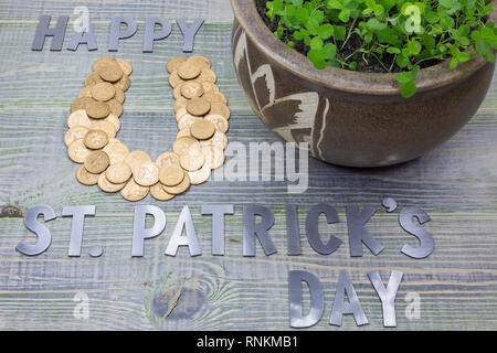 Symbol für Glück Hufeisen, mit britischen Goldmünzen gesäumt, Topf von Clover, Beschriftung in Briefen - St. Patricks Tag Stockfoto