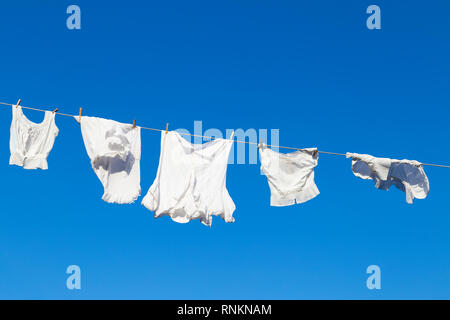 Saubere weiße Wäsche hängen an einem Seil gegen den blauen Himmel während einer schönen sonnigen Tag zu trocknen Stockfoto