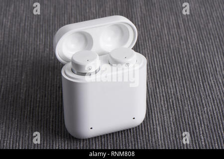 Wireless Bluetooth Ohrhörer mit aufladbaren Fall auf einem Stoff Hintergrund Stockfoto