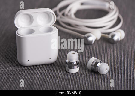 Wireless Bluetooth Ohrhörer mit aufladbaren Fall auf einem Hintergrund von Kabel Ohrhörer Stockfoto