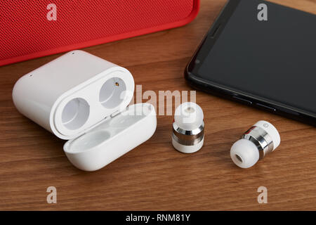 Wireless Bluetooth Ohrhörer und kostenpflichtigen Fall mit Smartphone und partable Lautsprecher Stockfoto