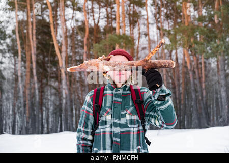 Wandern männliche Person im Winter Wald. Lächelnd Mann in karierten Winter shirt hält ein Protokoll der Pinienwald Stockfoto